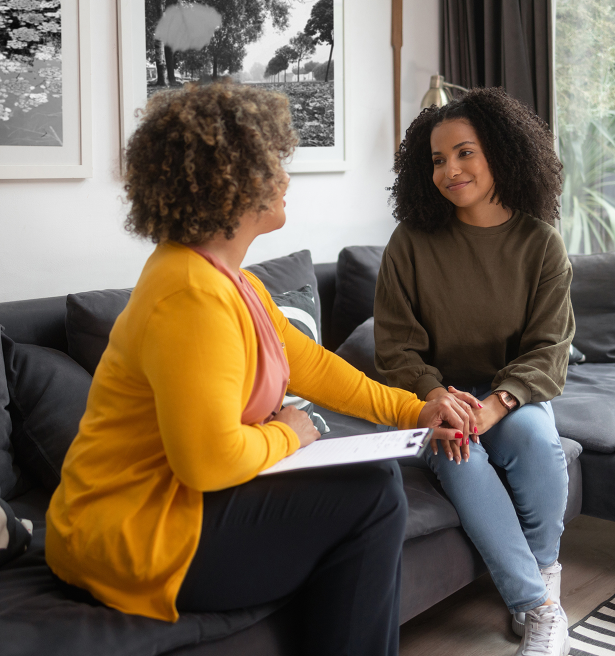 Two women talking on a couch, smiling.