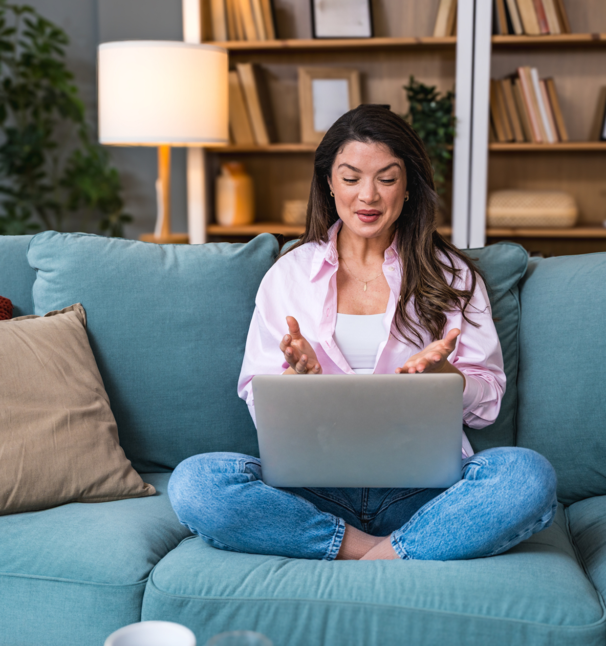 Woman video chatting on laptop from sofa.