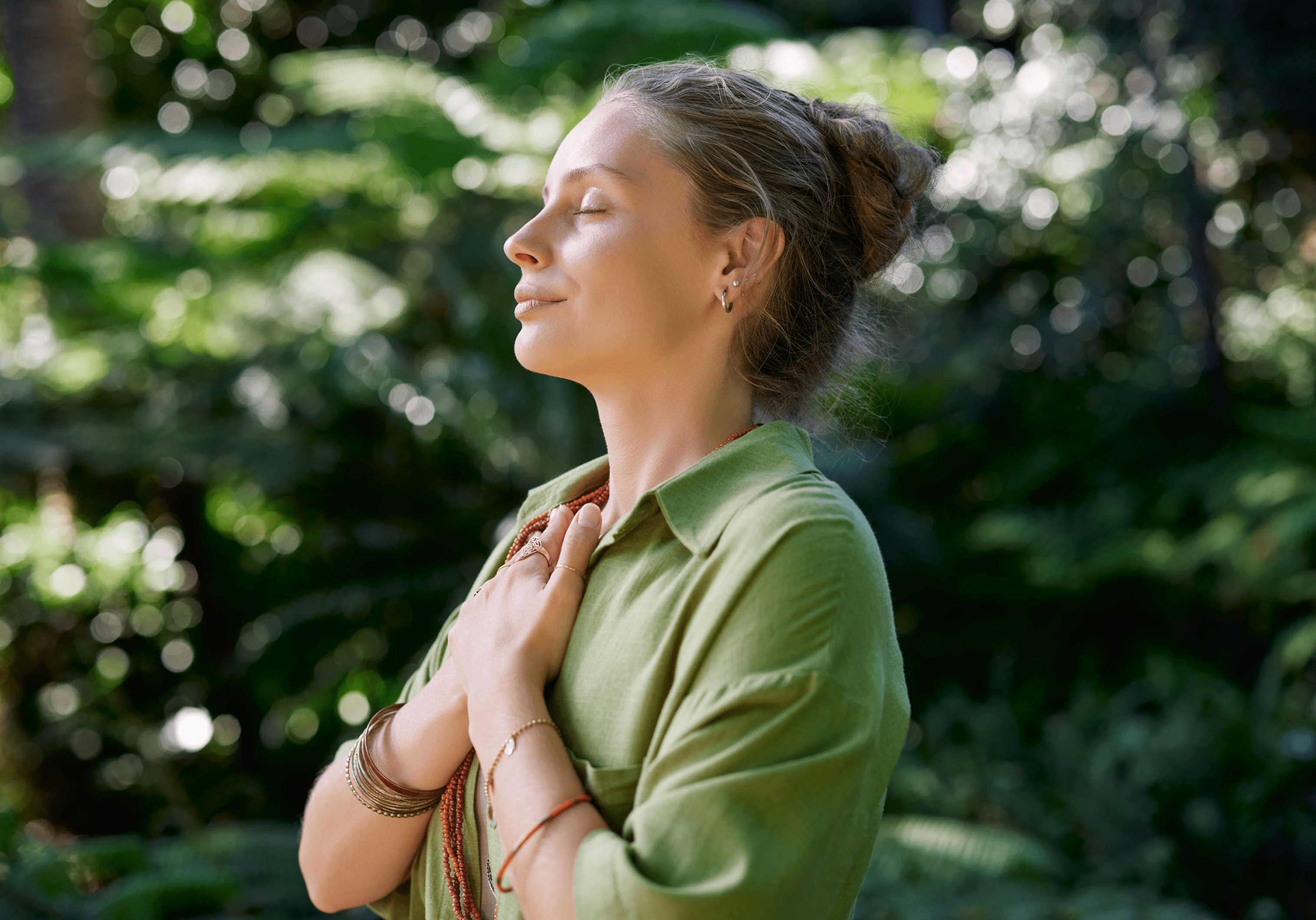 Woman meditating peacefully in green surroundings.